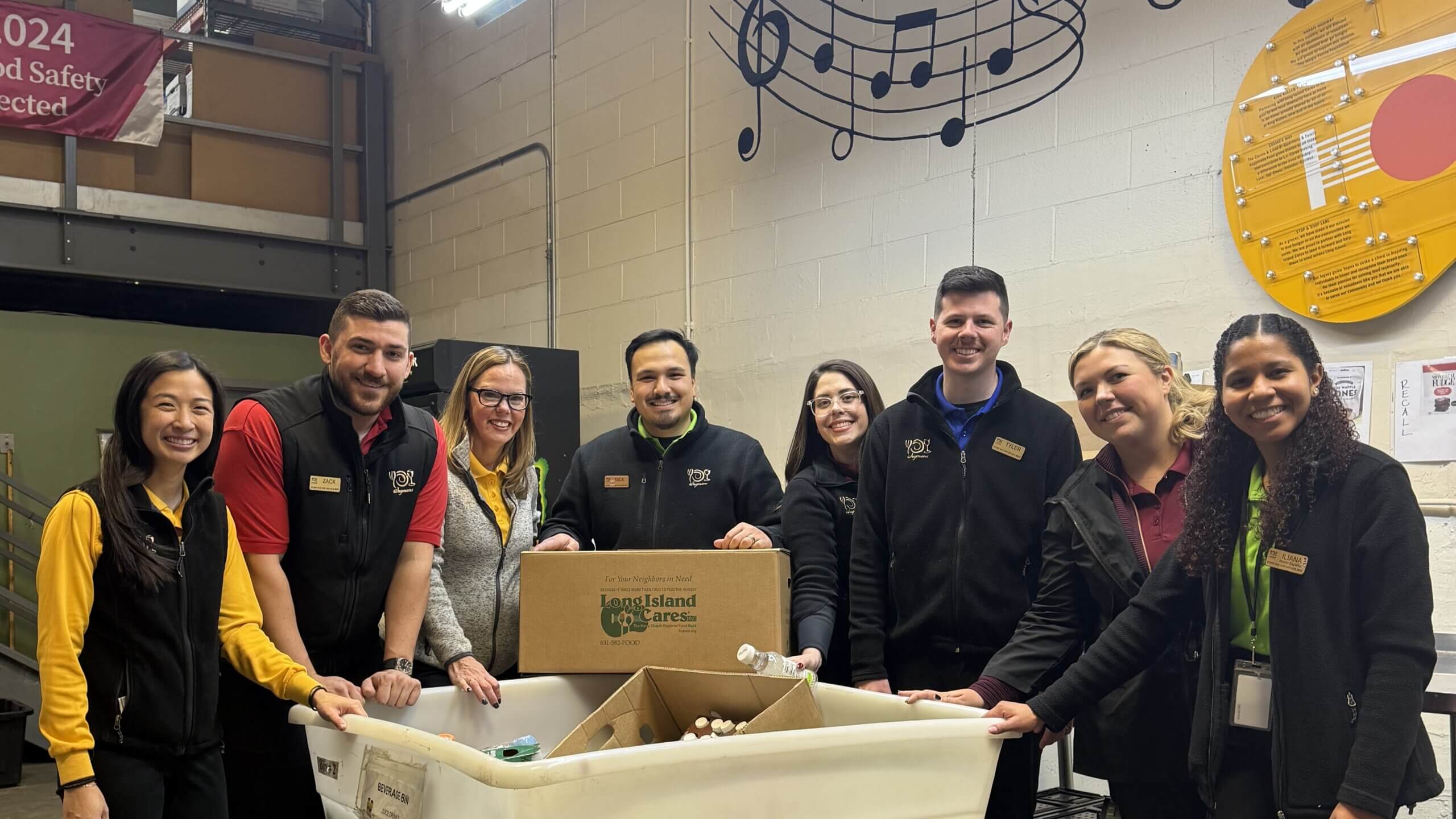 Lake Grove team members stand in front of donation bin with box reding 