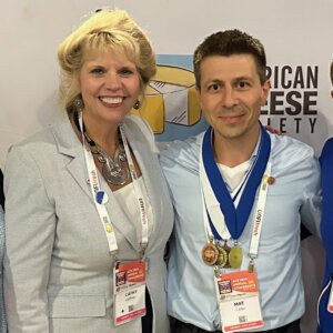 Woman and man smile at camera with four medals around the man's neck